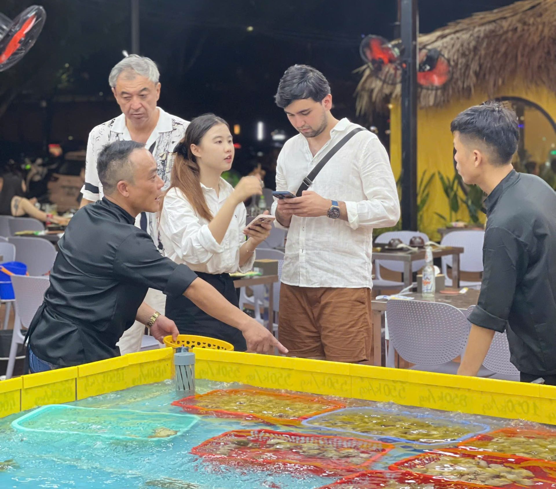 Customers choose quality seafood near the beach, freshly selected live from the tank